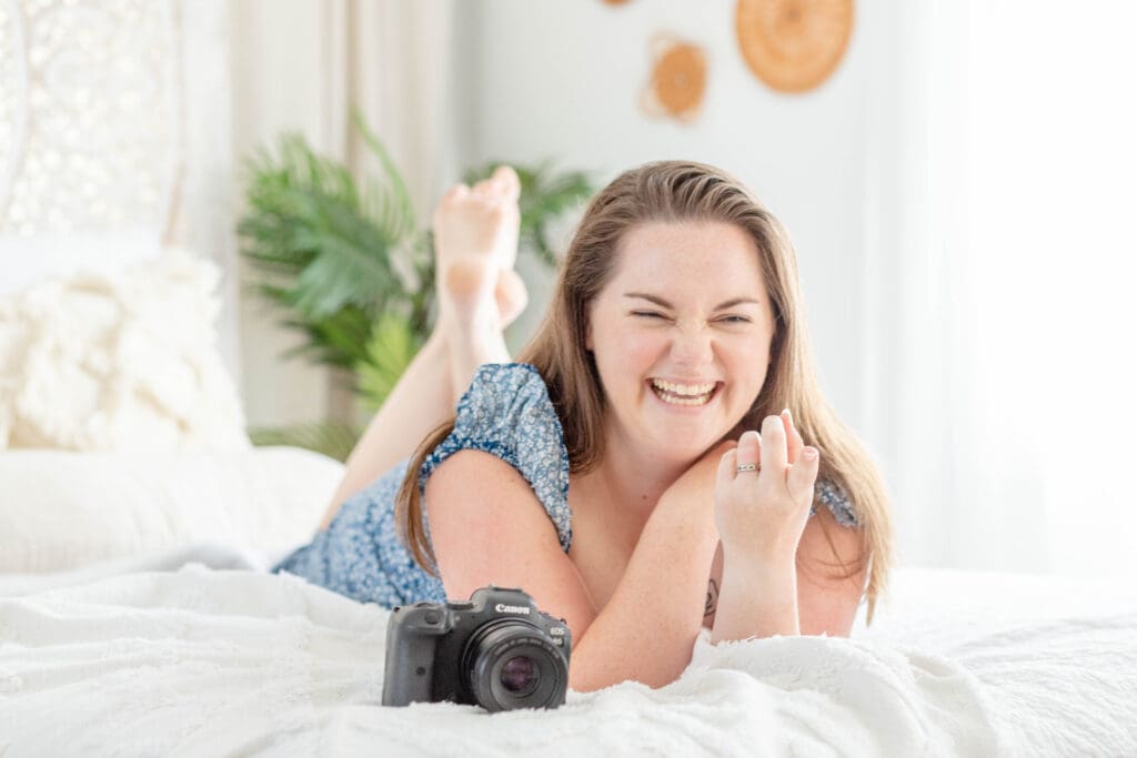 Woman laughing while lying on a bed next to her camera | Why small businesses need brand photos