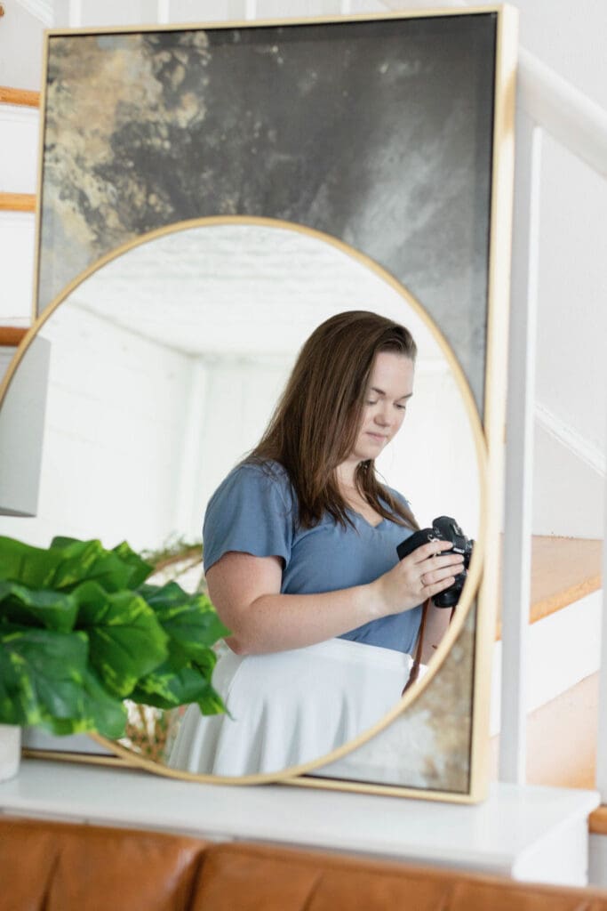 Reflection in round mirror of a woman looking down at her camera | What to Wear for Your Brand Photos