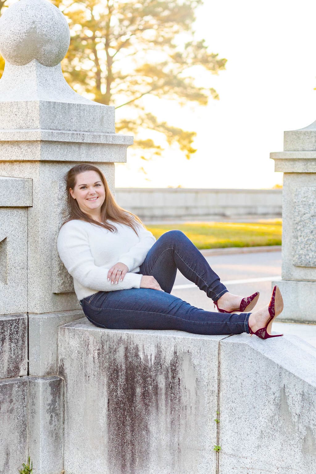 Woman sits on concrete stairs casually leaning back on a pillar |